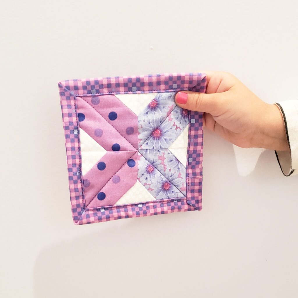 Image of someone holding a cute finished quilting pattern coaster