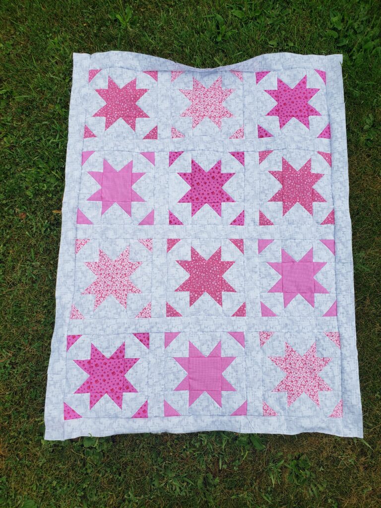 Image of a quilt with pink stars and triangles