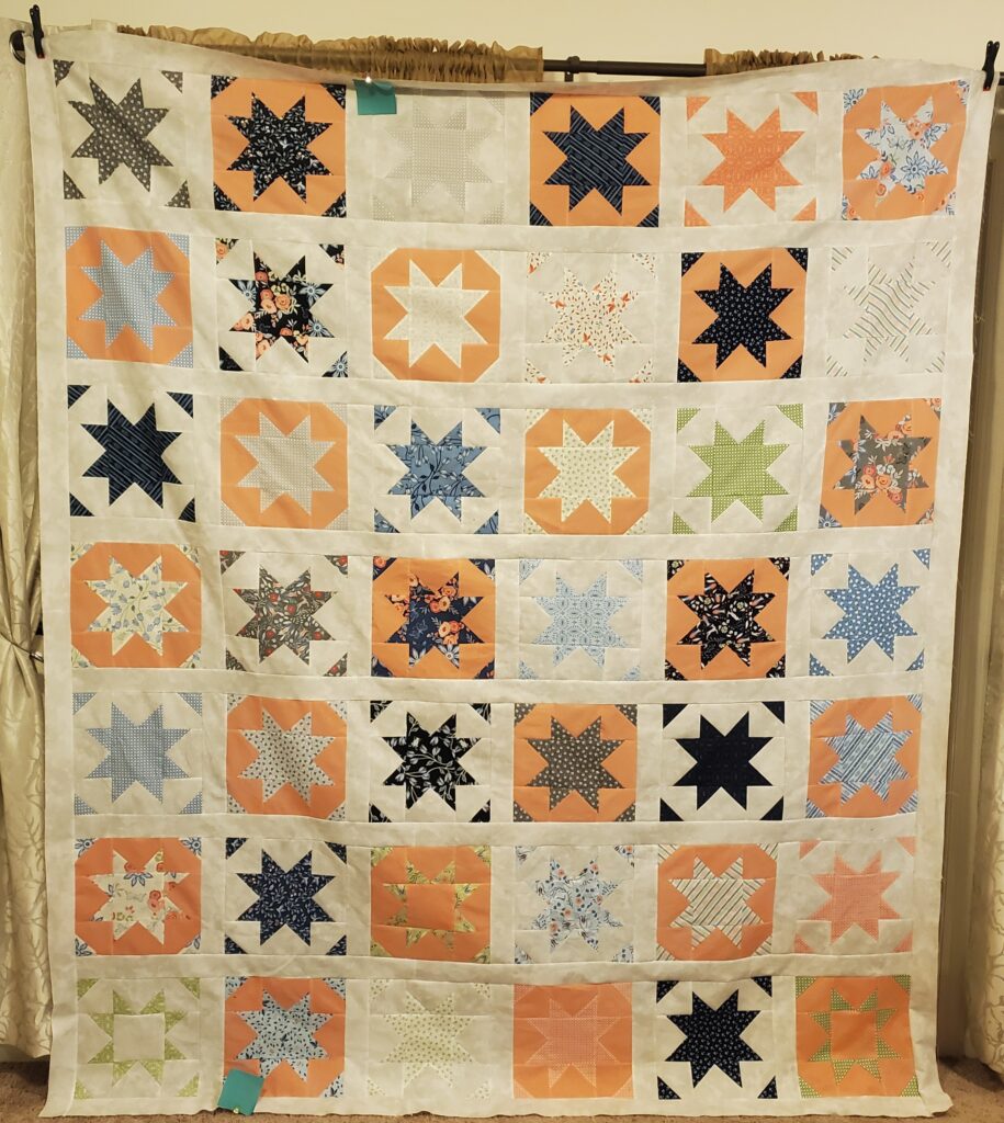 Alisha's quilt with fun orange and colorful stars and triangles 